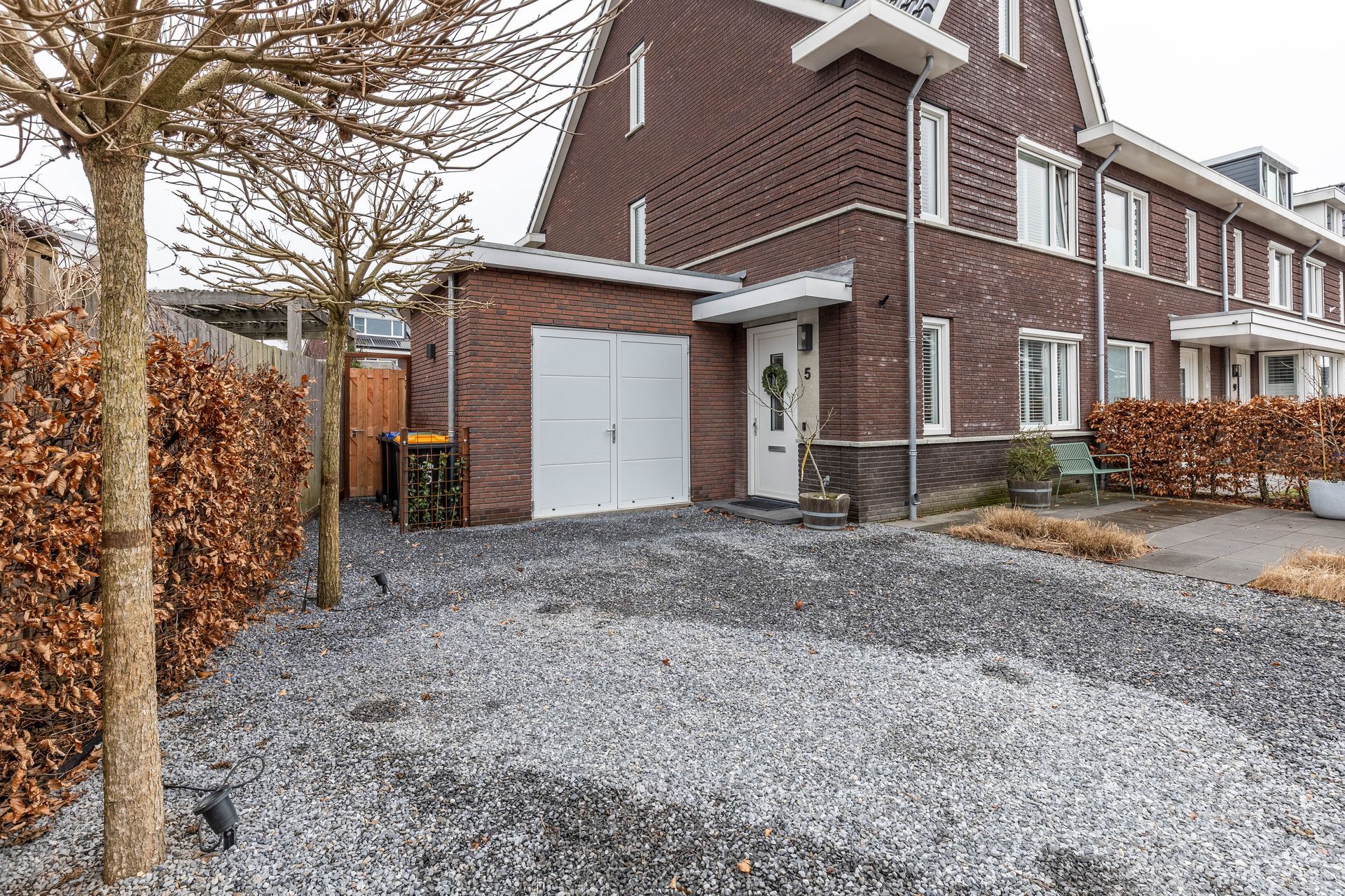 Bakstenen garage aanbouw wit. Gravel terras oprit. Verbouwing uitbouw