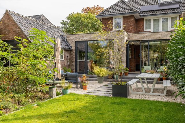 Gerealiseerde aanbouw met glazen deuren en moderne tuin bij woning