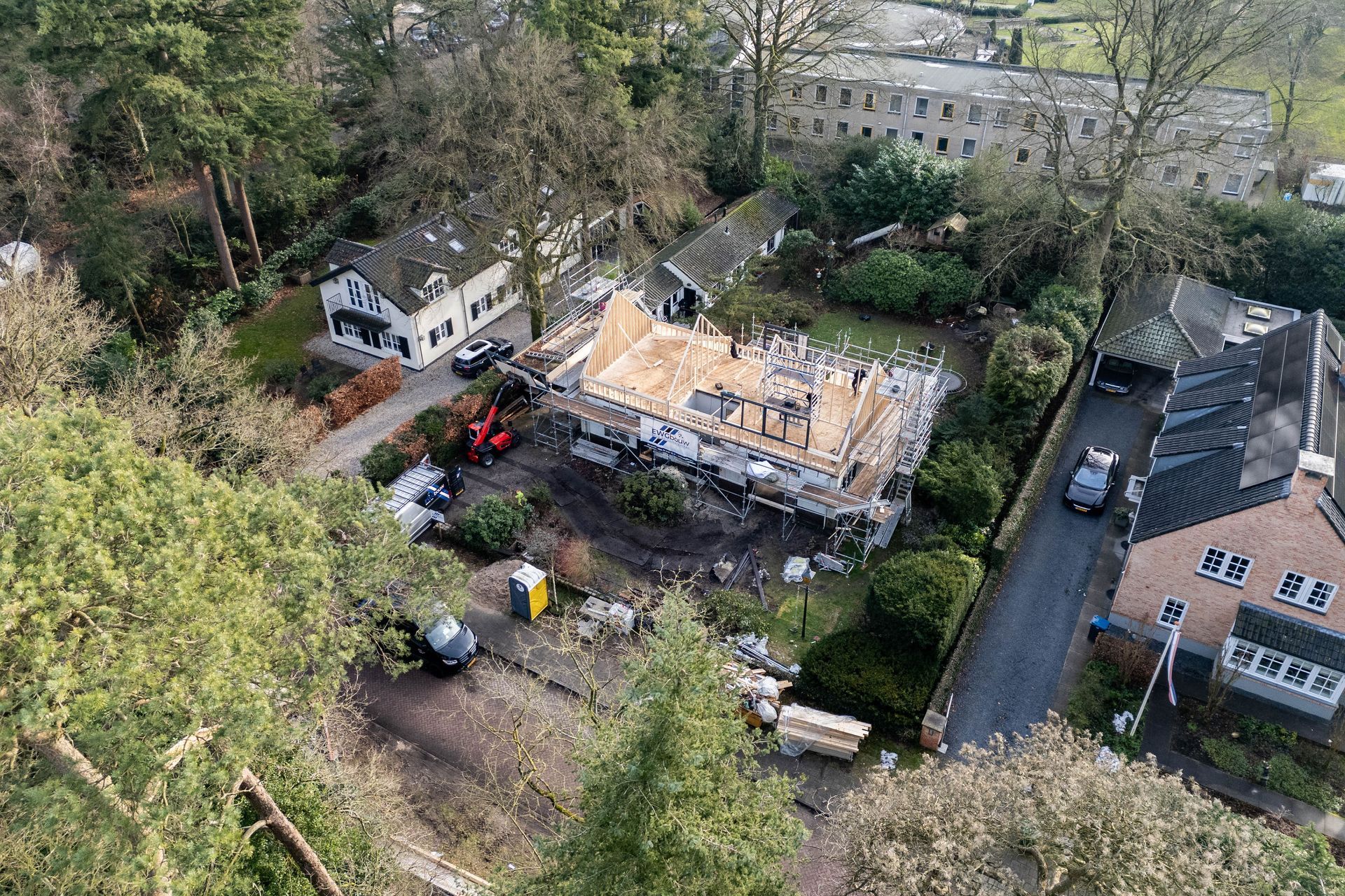 Luchtfoto dakwerk in aanbouw. Dakrenovatie woning met steiger en materieel zichtbaar.