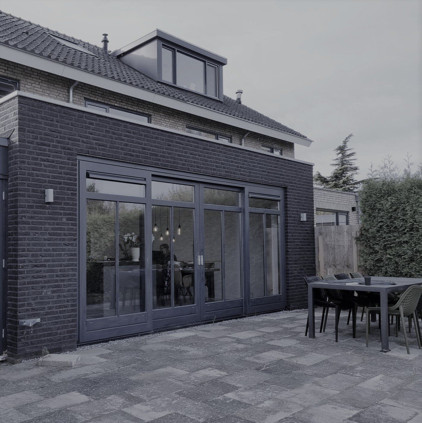 Moderne zwarte voorgevel met grote raampartijen. renovatie woning.