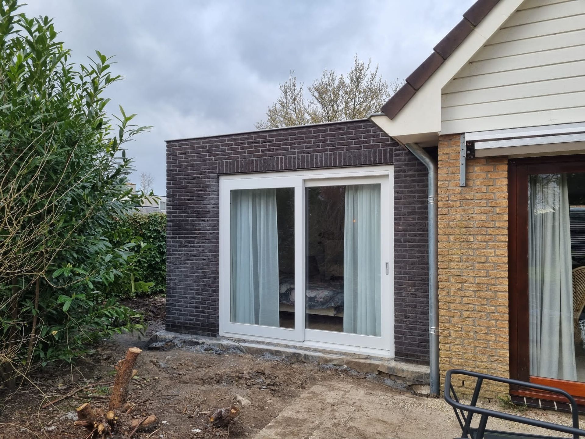 Donkere bakstenen aanbouw met ramen. Moderne aanbouw en verbouwing renovatie.
