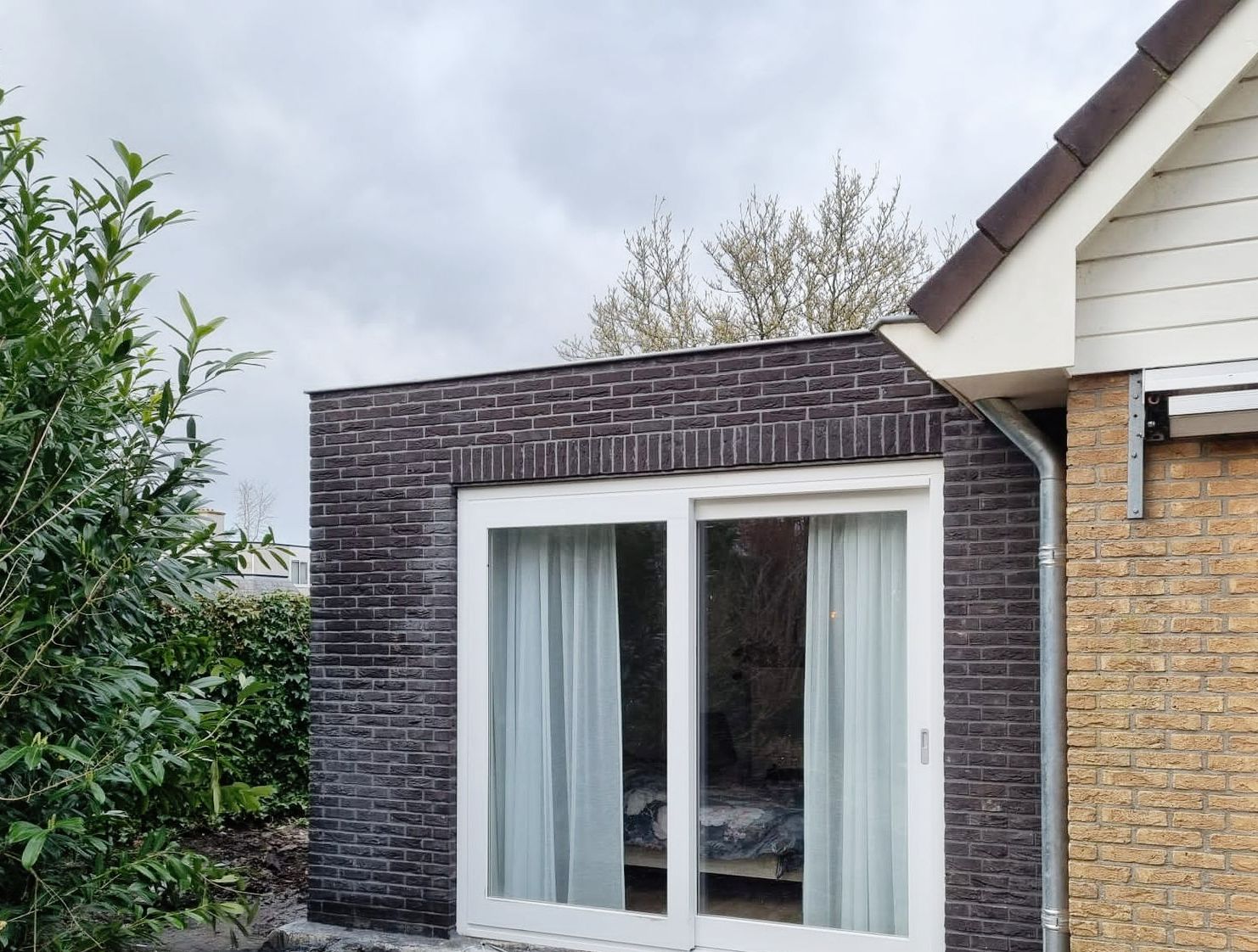 Donkere bakstenen aanbouw met witte deuren. Verbouwing aanbouw en renovatie moderne.