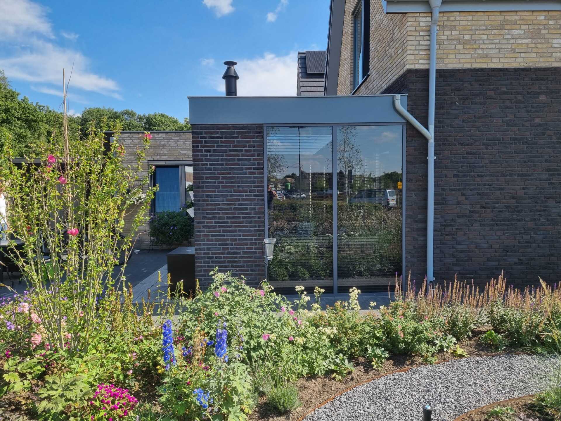 Moderne bakstenen aanbouw met grote ramen. Verbouwing en uitbreiding woning.