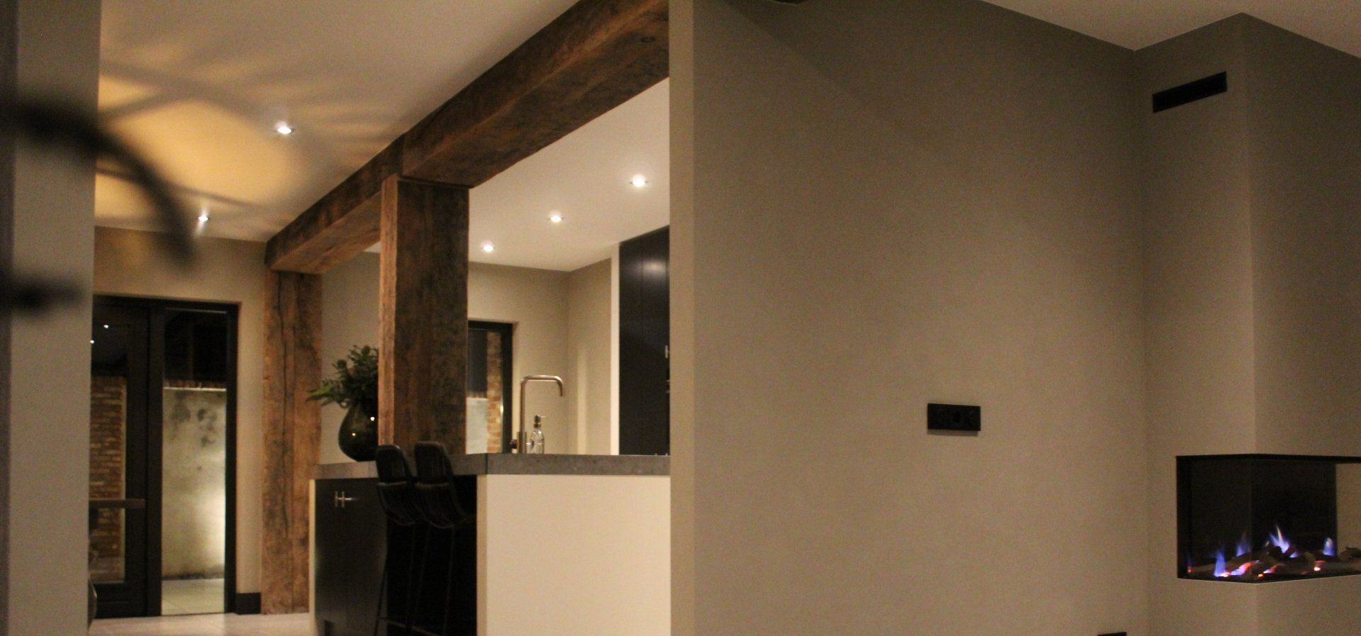 Interieur woonkamer met houten balk en moderne verlichting. Verbouwing woonruimte door bouwbedrijf.