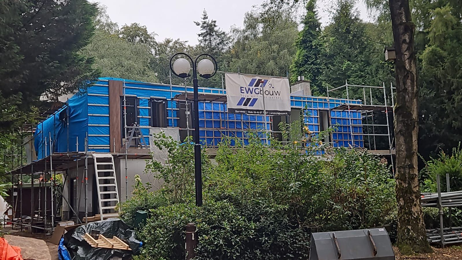Blauwe container woning steigers in bouw. Aannemer container bouw alternatief wonen.