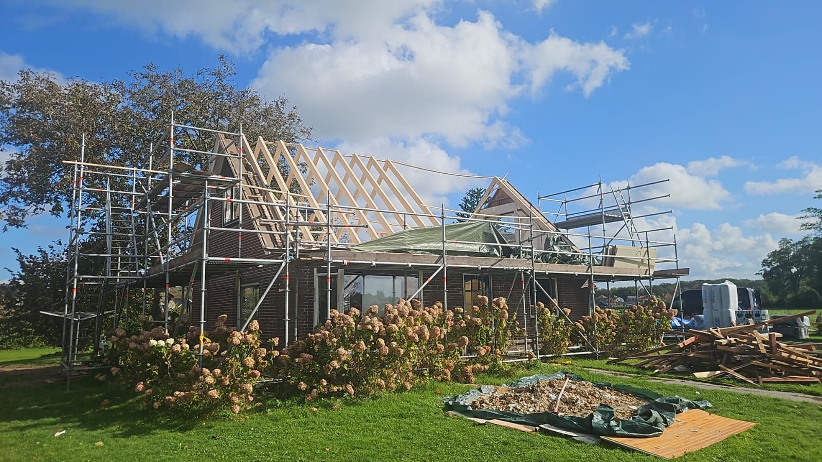 Woning in aanbouw met houten dakstructuur en bouwsteiger. Woningbouw en dakconstructie.