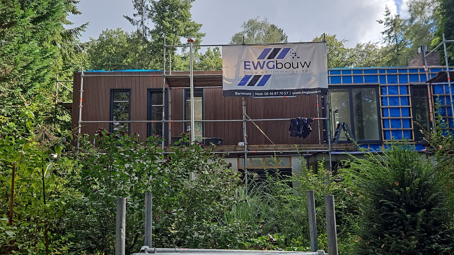 Moderne woning in aanbouw met EWG bouw banner. Woningbouw en aanbouwwerk.
