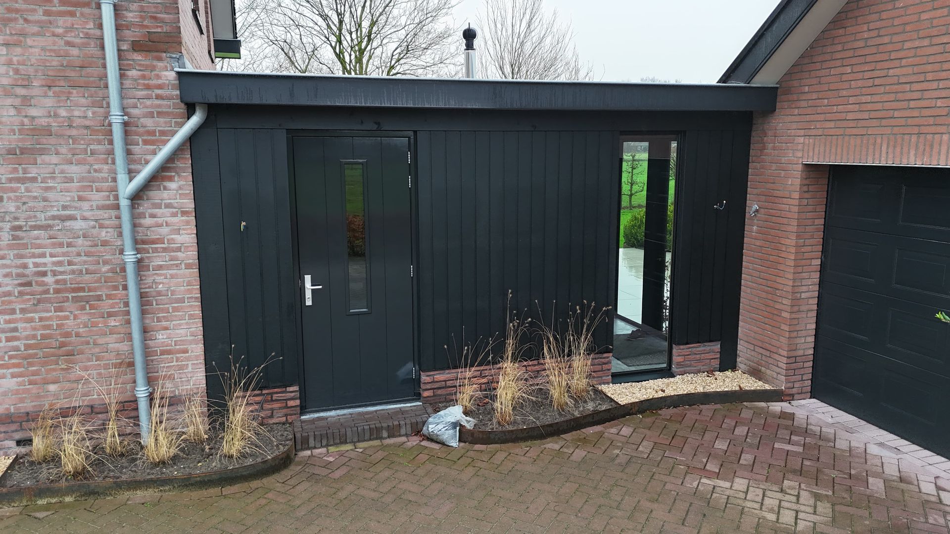 Moderne zwarte aanbouw garagestructuur aan woning. Garageboxen en woninguitbouw.