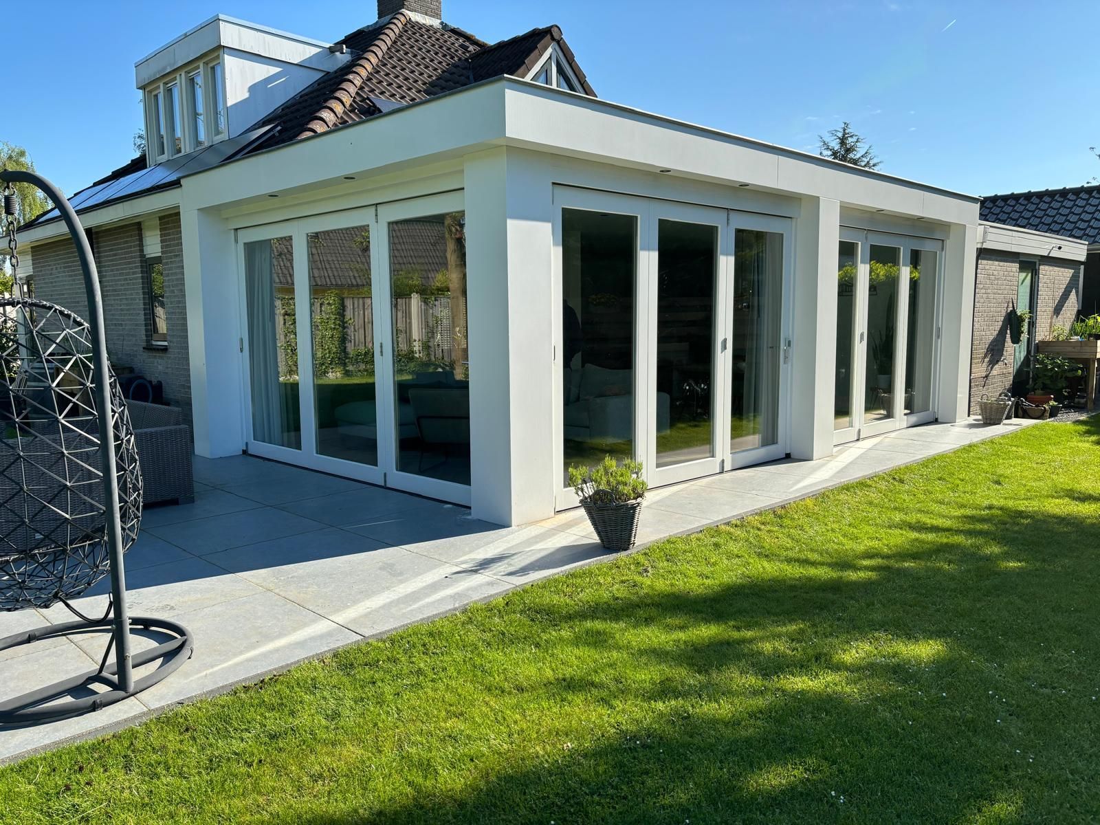 Gerenoveerde tuinuitbouw met glazen openslaande deuren. Verbouwing woning door aannemer.
