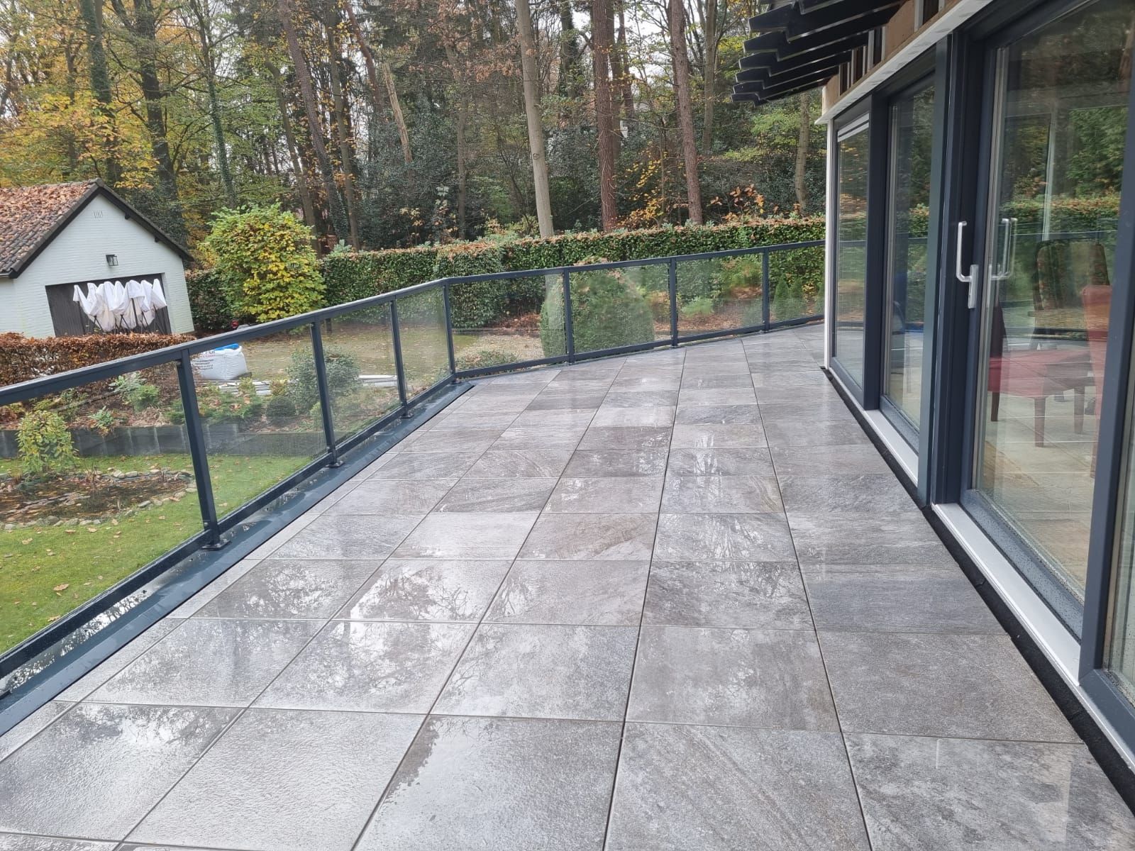 Nieuw betegeld terras met glazen balustrade na verbouwing