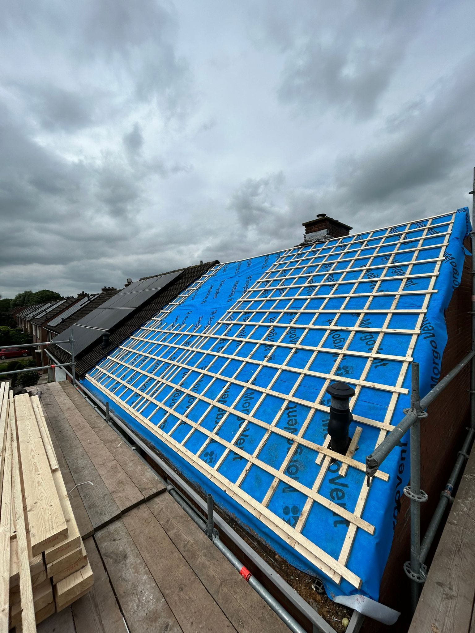Dak met blauwe bescherming en dakwerk. Dakrenovatie en verbouwing dakconstructie.