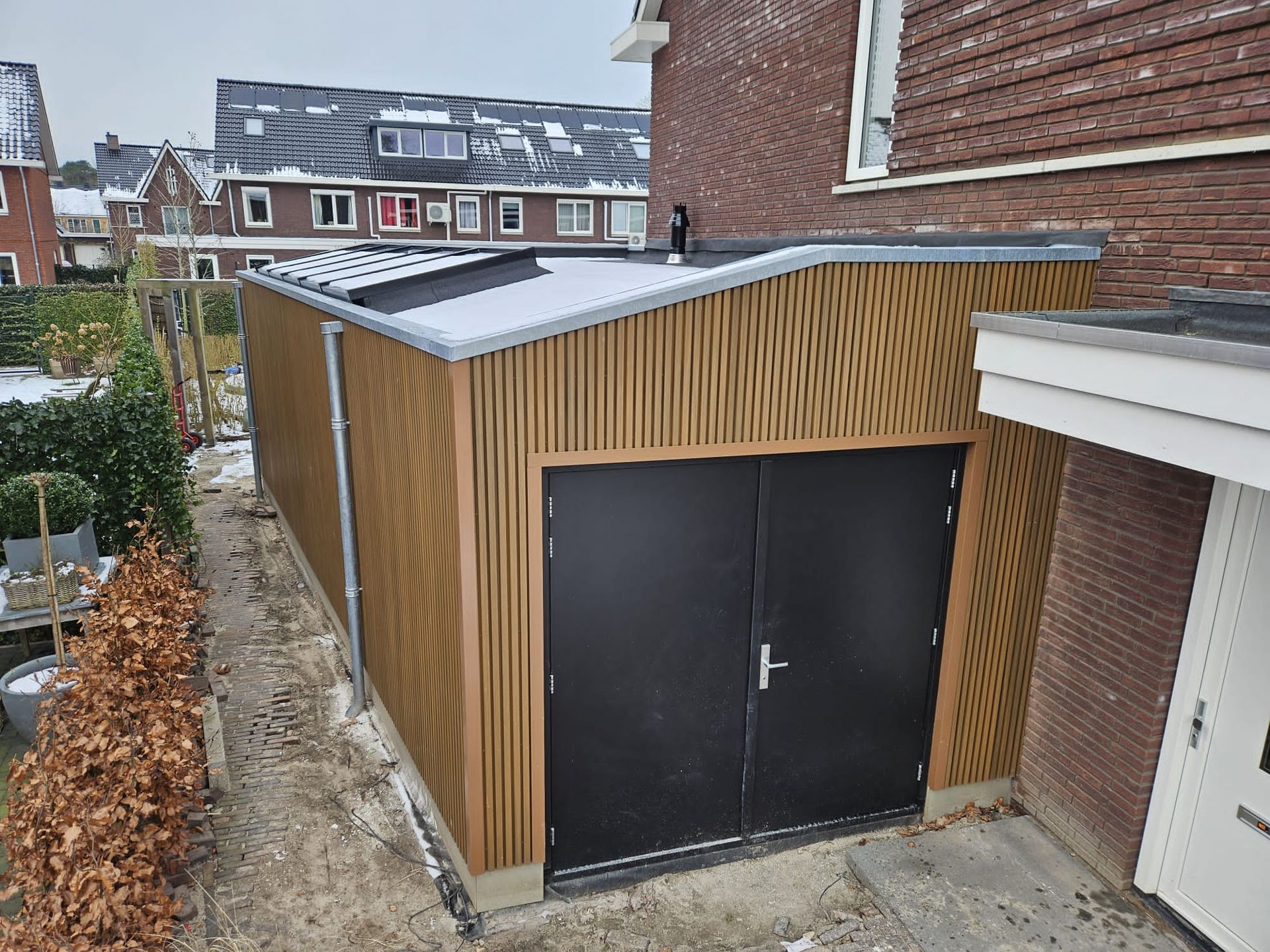 Houten aanbouw met dak afgewerkt. Garagestructuur en woninguitbouw.