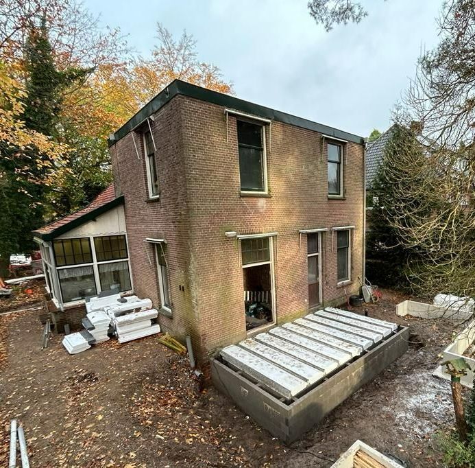 Zijkant bakstenen huis met aanbouw in voorbereiding. Verbouwing en renovatie project.