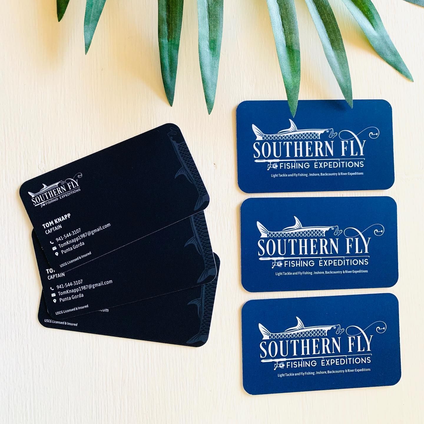 Black and blue business cards for Southern Fly Fishing Expedition on a light surface
