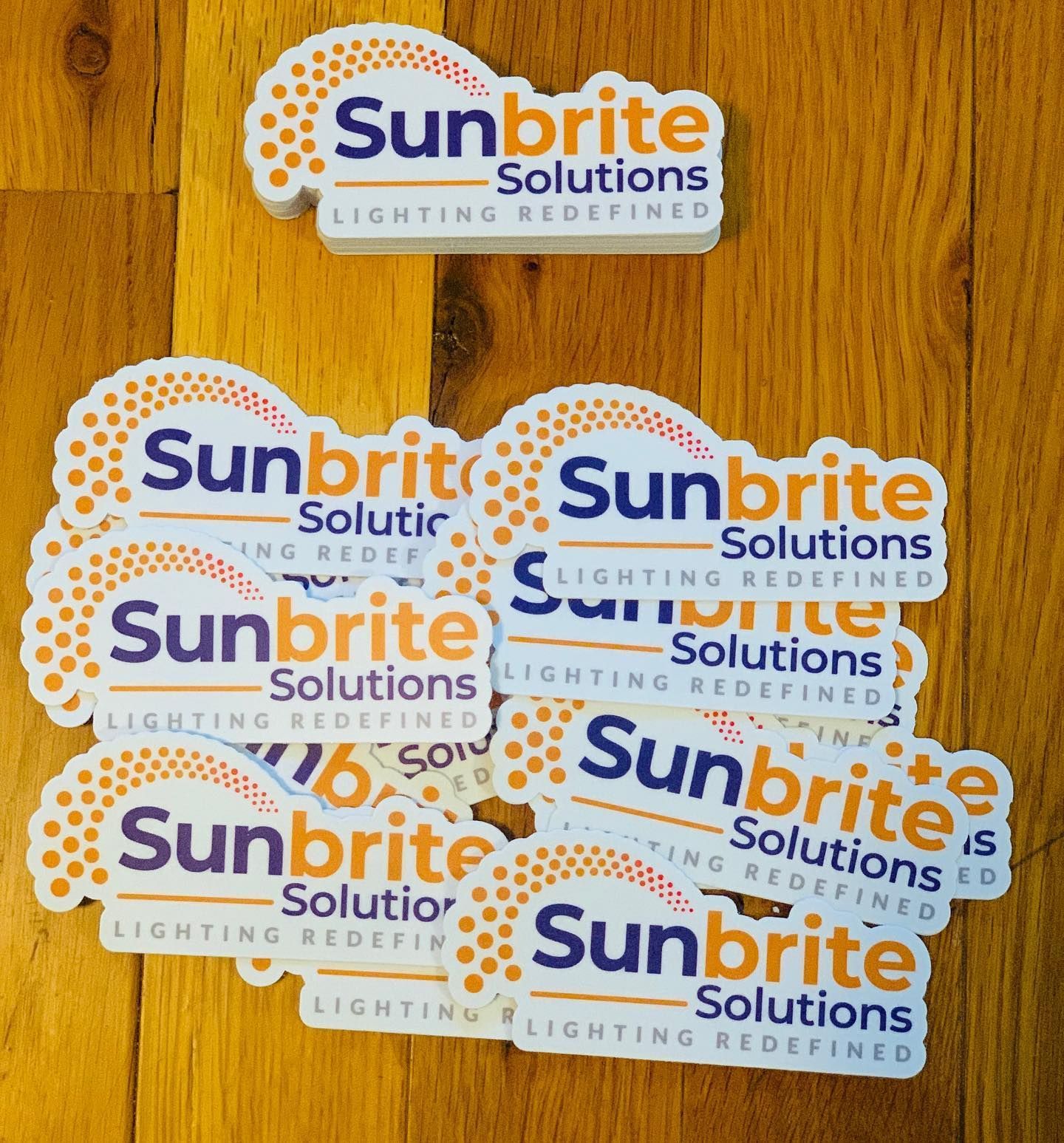 Assorted Sunbrite Solutions lighting sticker labels on a wooden surface