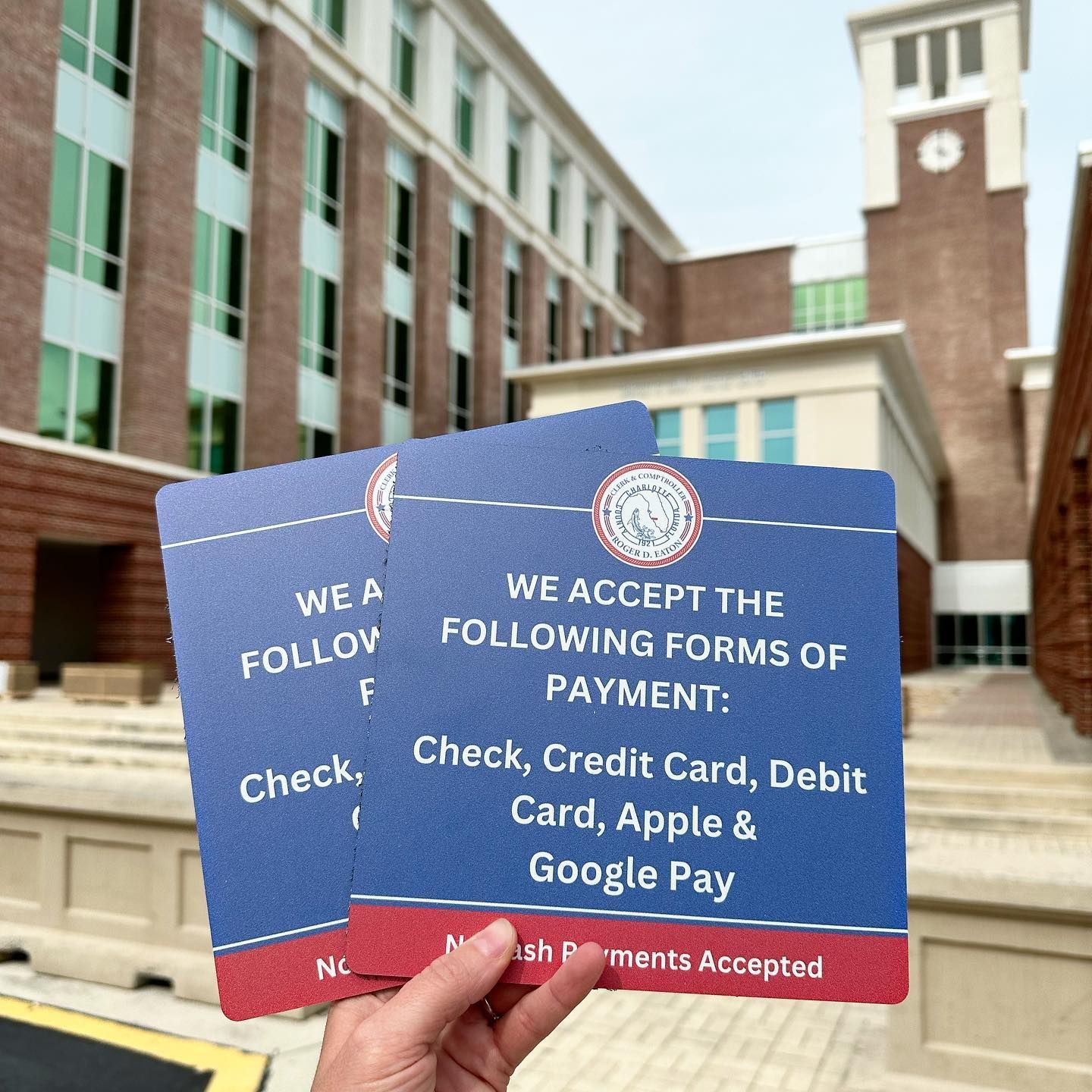 Blue payment signs listing check, credit, debit, Apple Pay and Google Pay in front of a building
