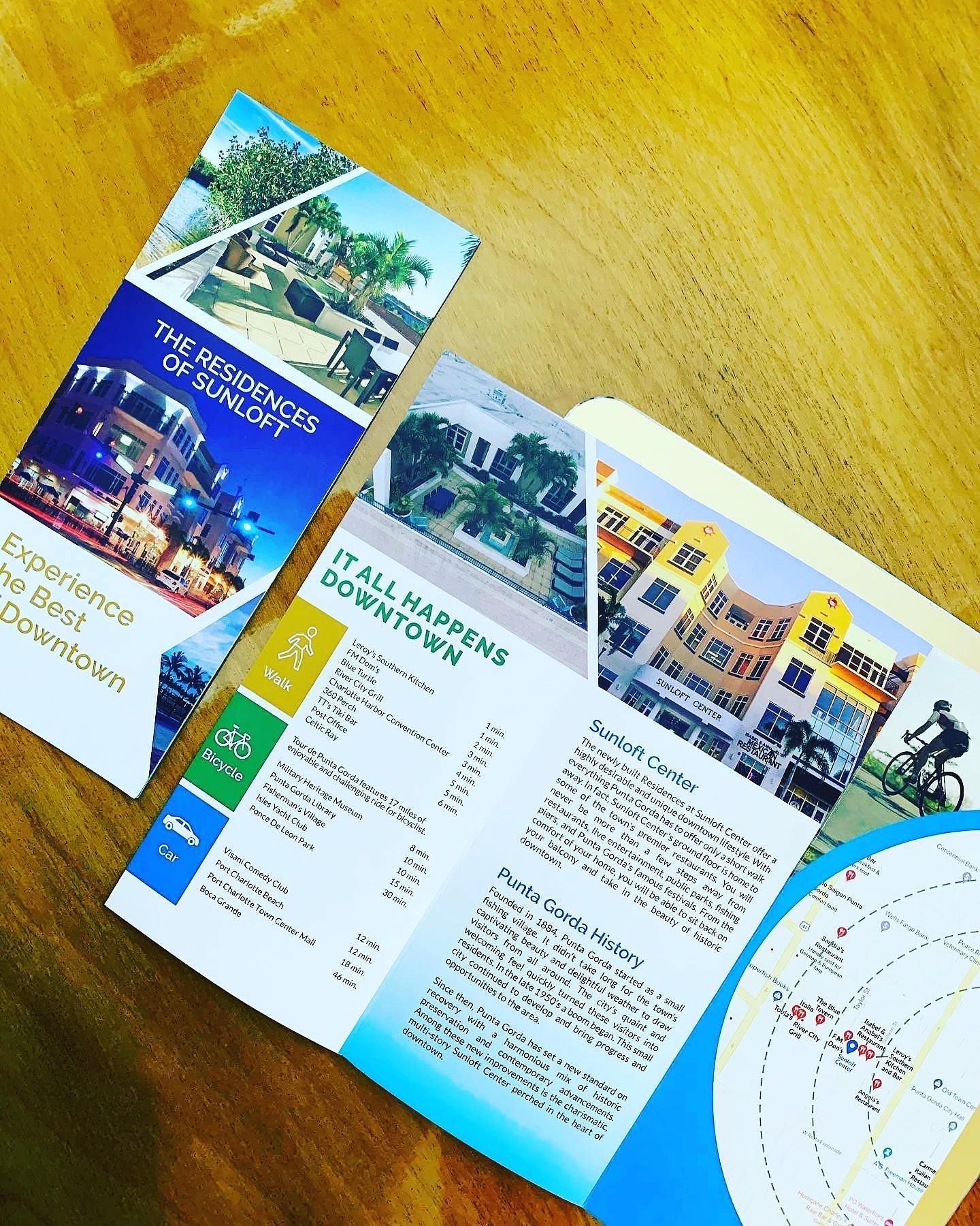 Three colorful travel brochures fanned on a wooden table, showing resort photos and maps.