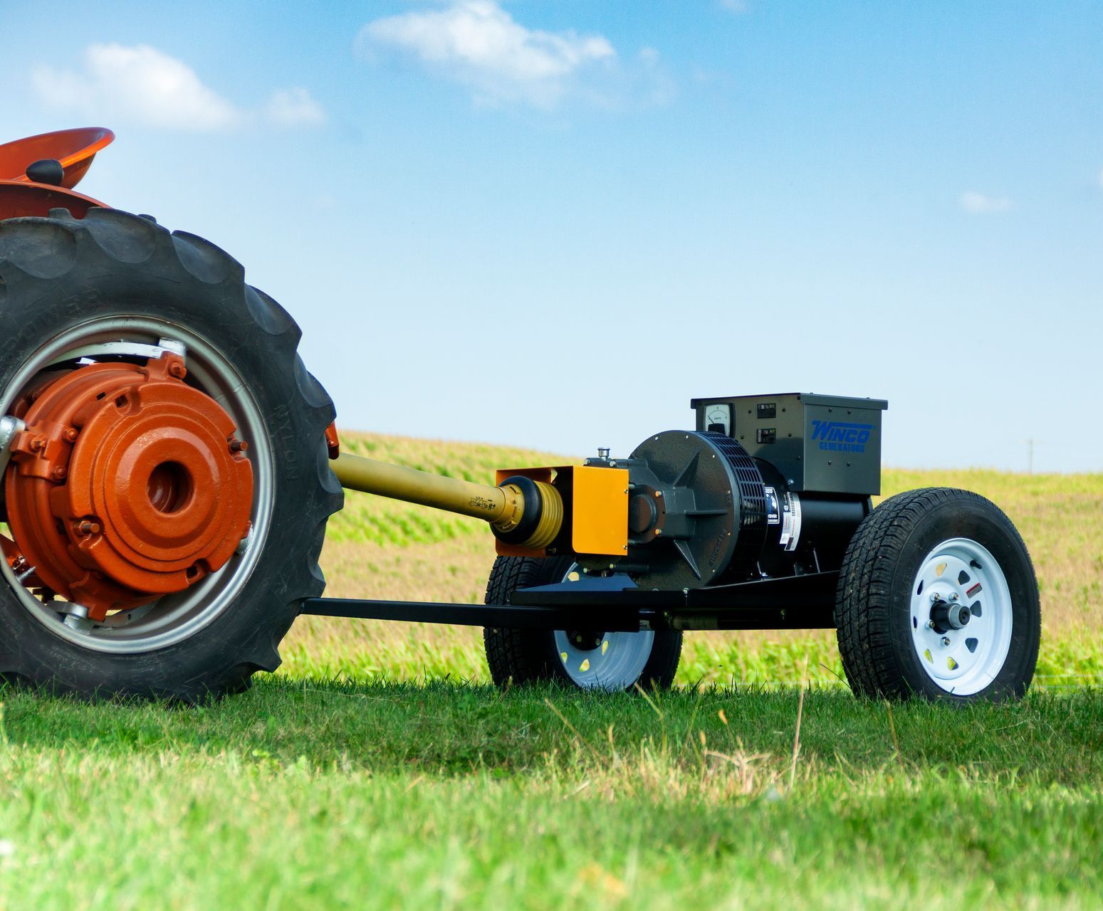 A tractor with a generator attached to it is parked in a grassy field.