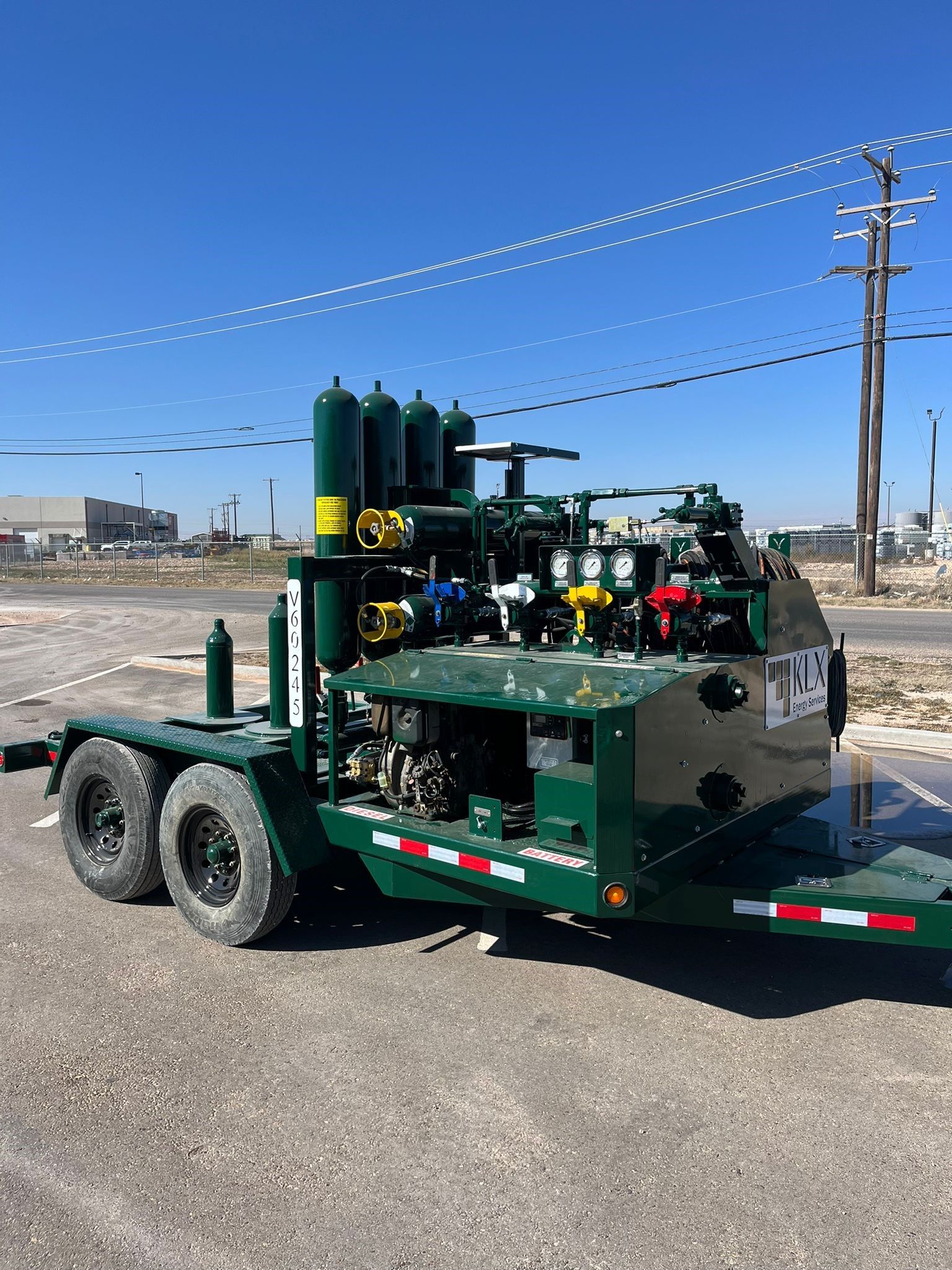 A green trailer with a machine on it is parked on the side of the road.