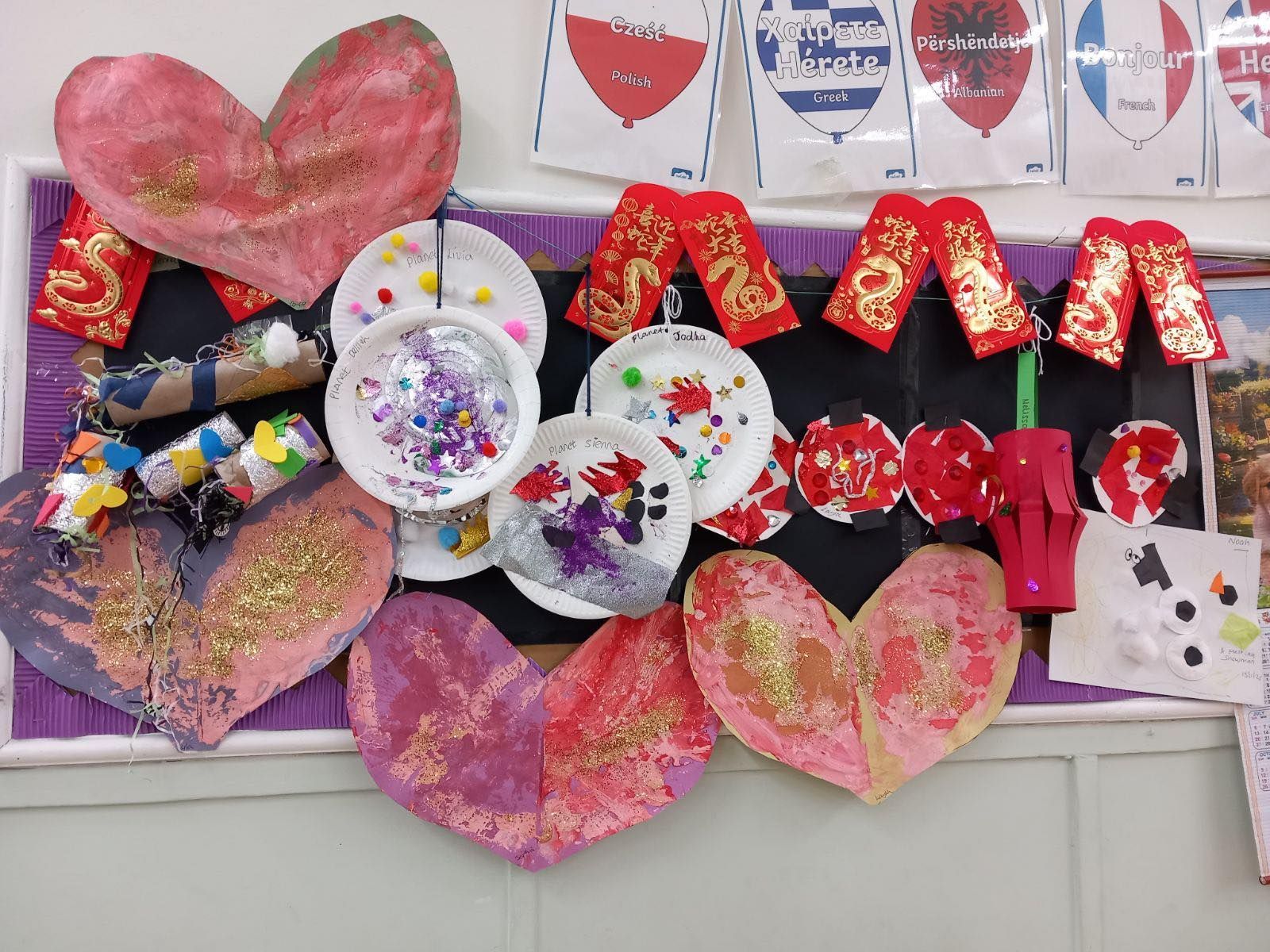 Arts and crafts display: hearts, paper plates, and red and gold decorations on a bulletin board.