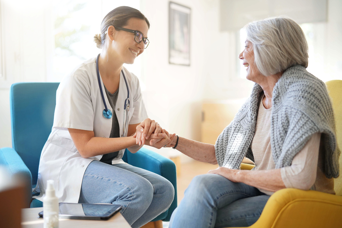 leadmonkey.ai | A nurse is holding the hand of an elderly woman.