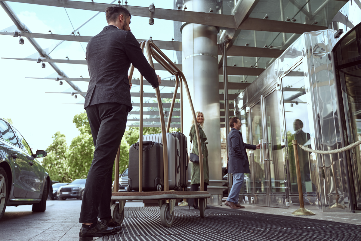 leadmonkey.ai | A man is pushing a cart with luggage into a hotel.