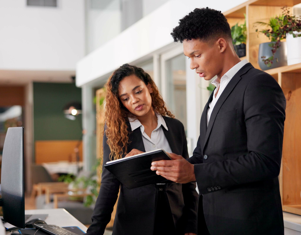 leadmonkey.ai | A man and a woman are looking at a clipboard in an office.