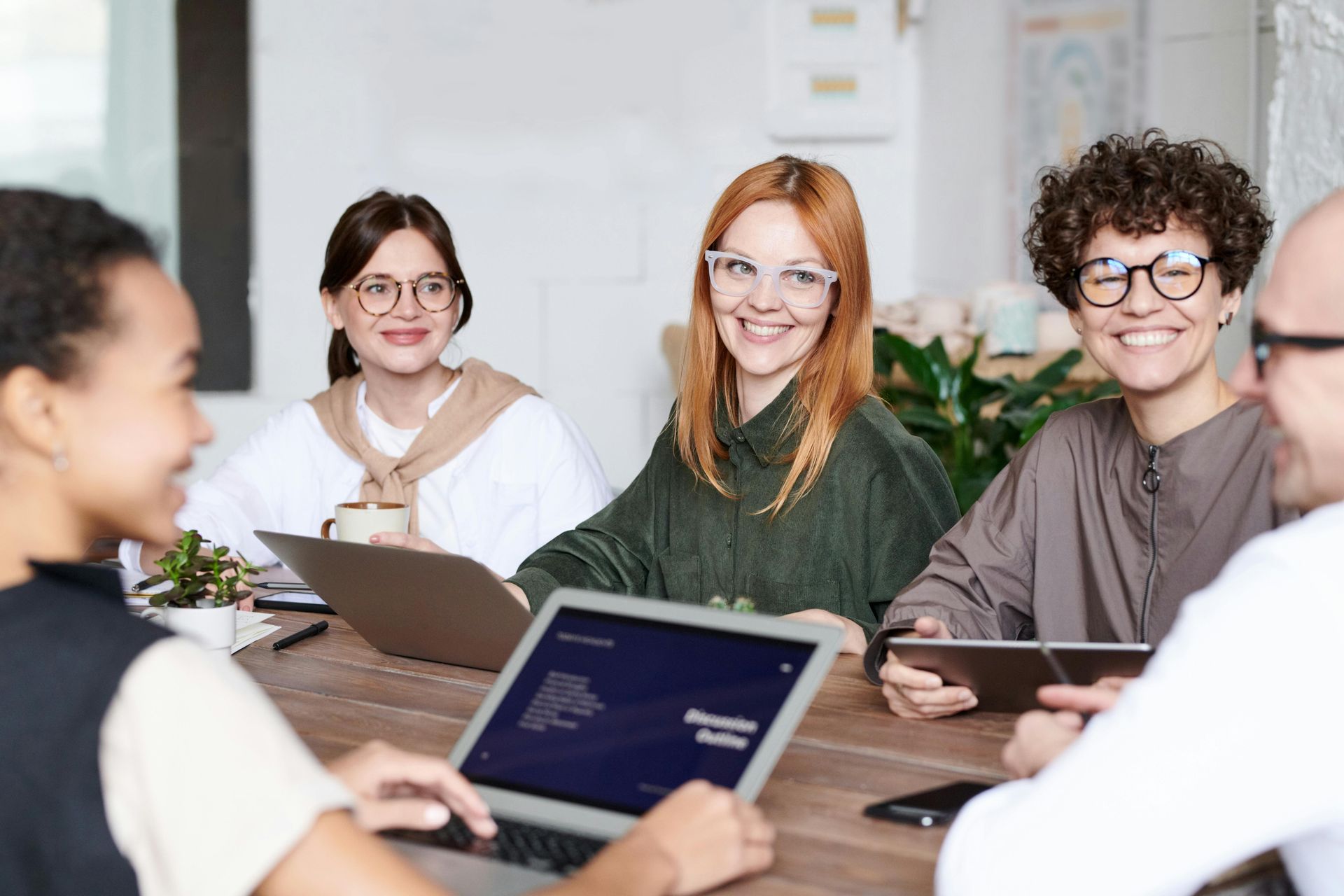 leadmonkey.ai | A group of people are sitting around a table with laptops and tablets.