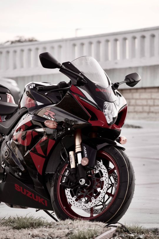 A red and black motorcycle is parked on the side of the road.