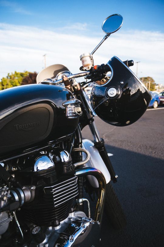 A close up of a motorcycle with a helmet on the handlebars.