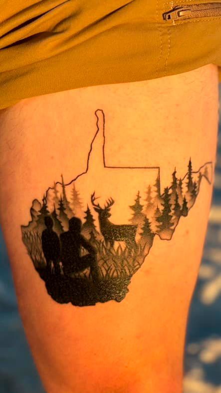 Tattoo of a line-art hand holding a forest silhouette on a person’s upper thigh