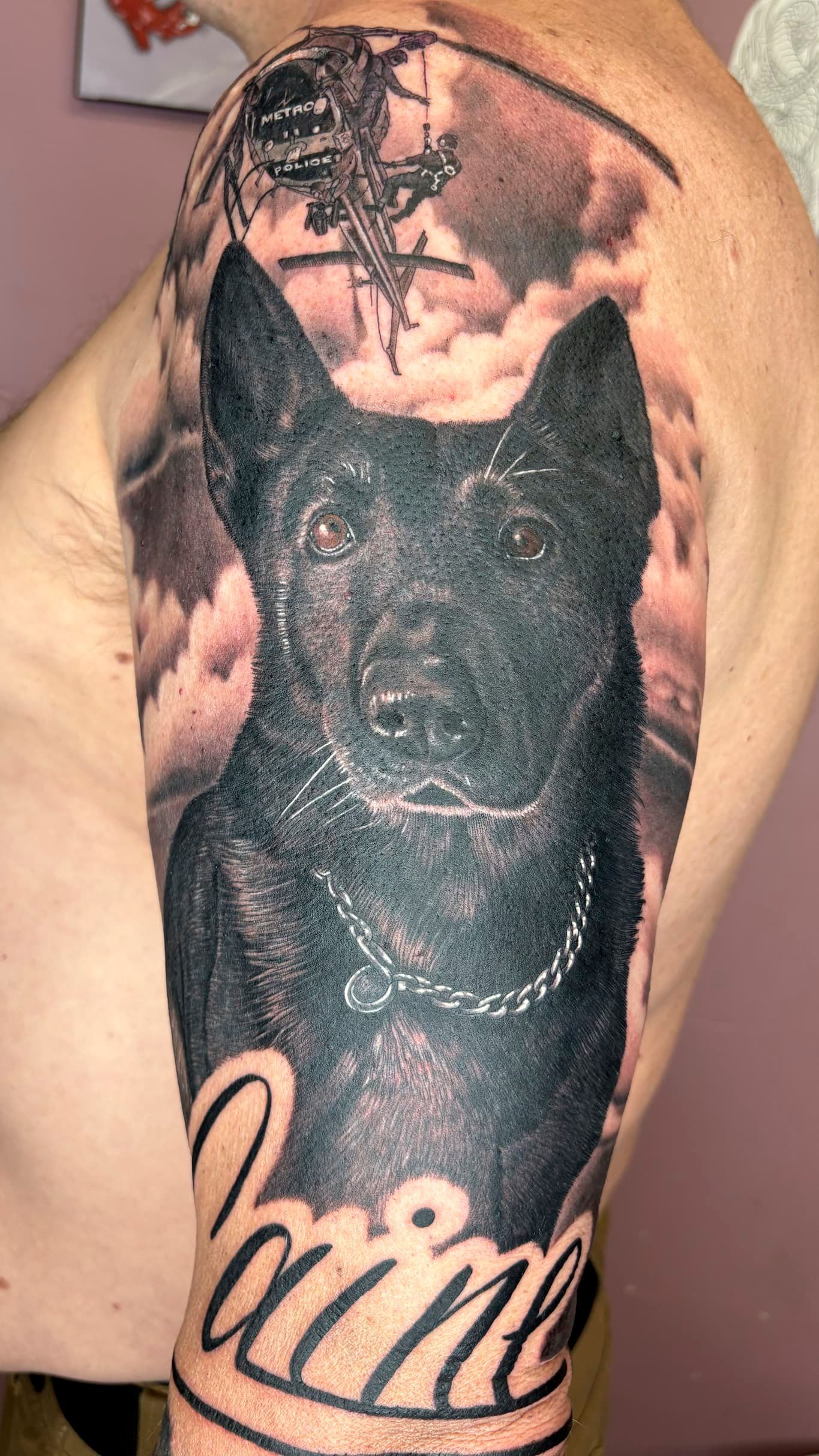 Close-up of a dark arm tattoo showing a portrait in black and gray ink.