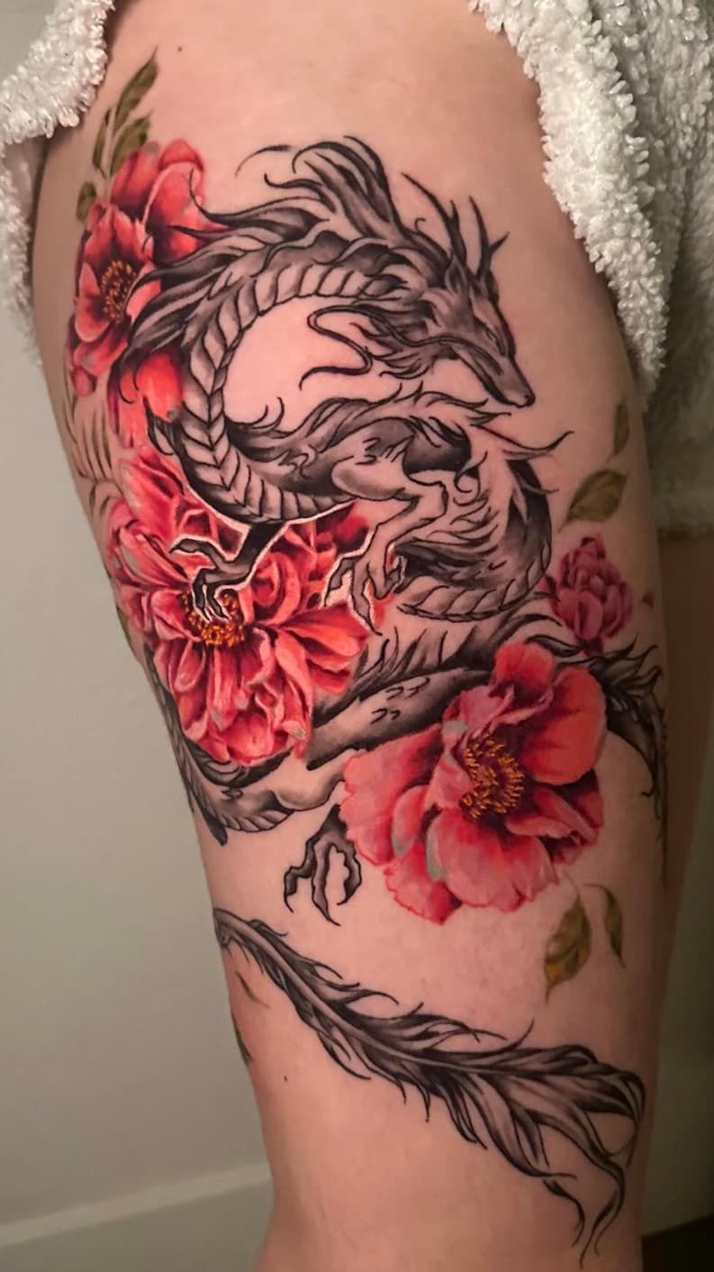 Black-and-red floral dragon tattoo on a person’s upper arm and shoulder