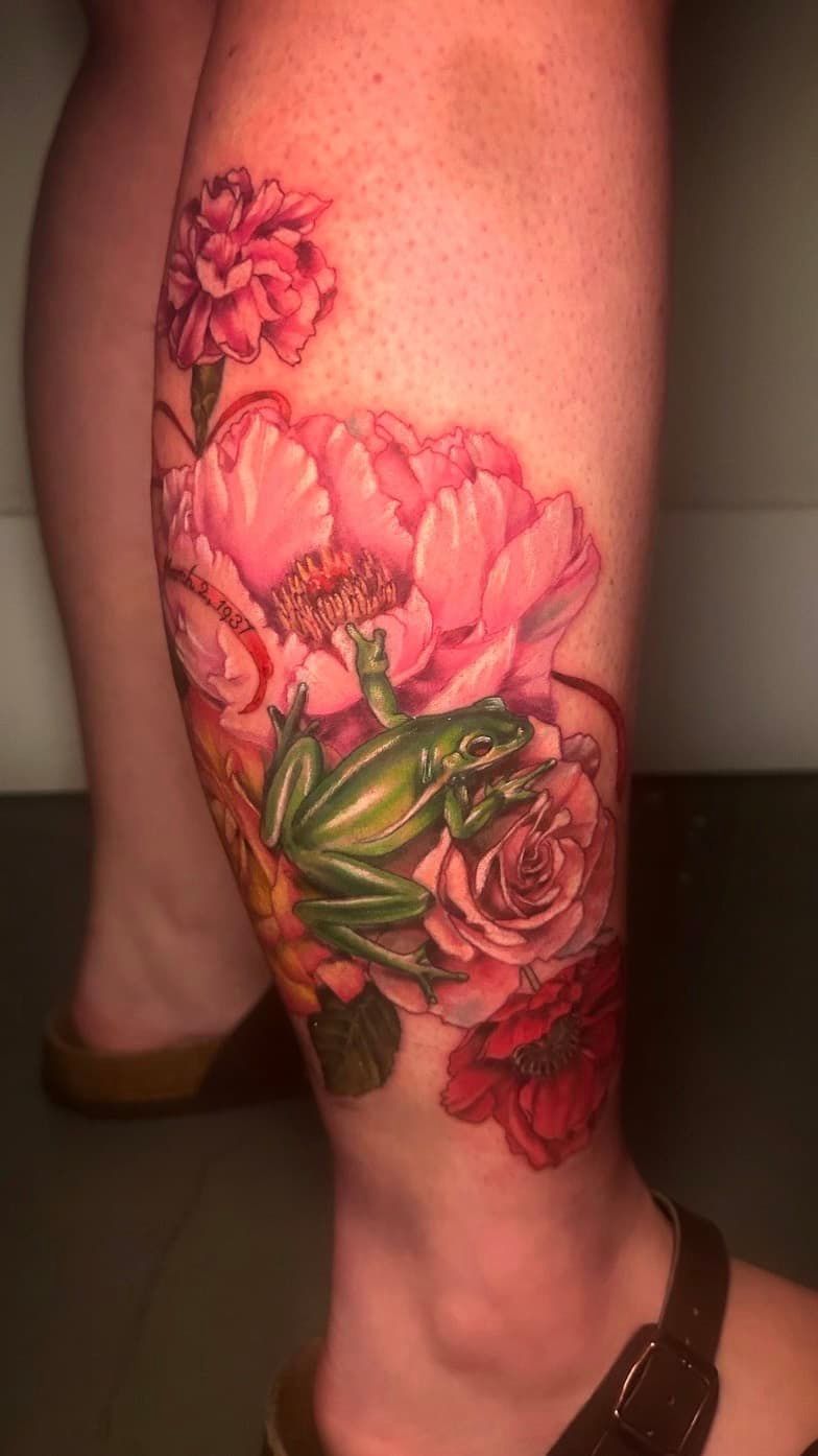 Colorful floral tattoo on the calf and ankle, featuring pink flowers and green leaves.