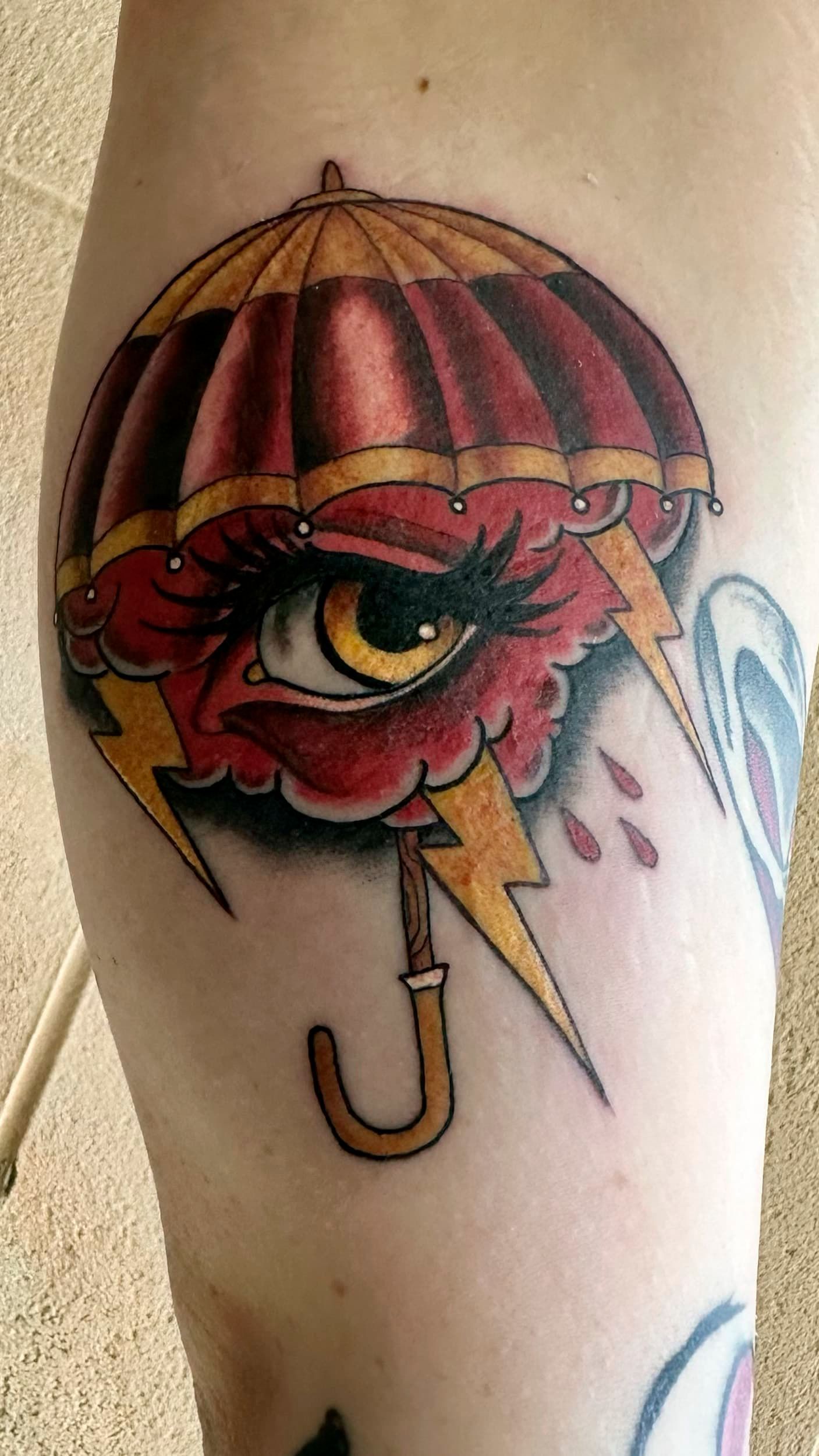 Umbrella tattoo with a red eye and a yellow lightning-bolt hook handle
