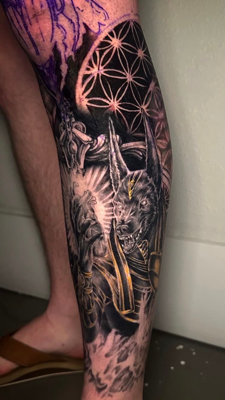 Black and gold tattoo of a moth and moon phases on a lower leg