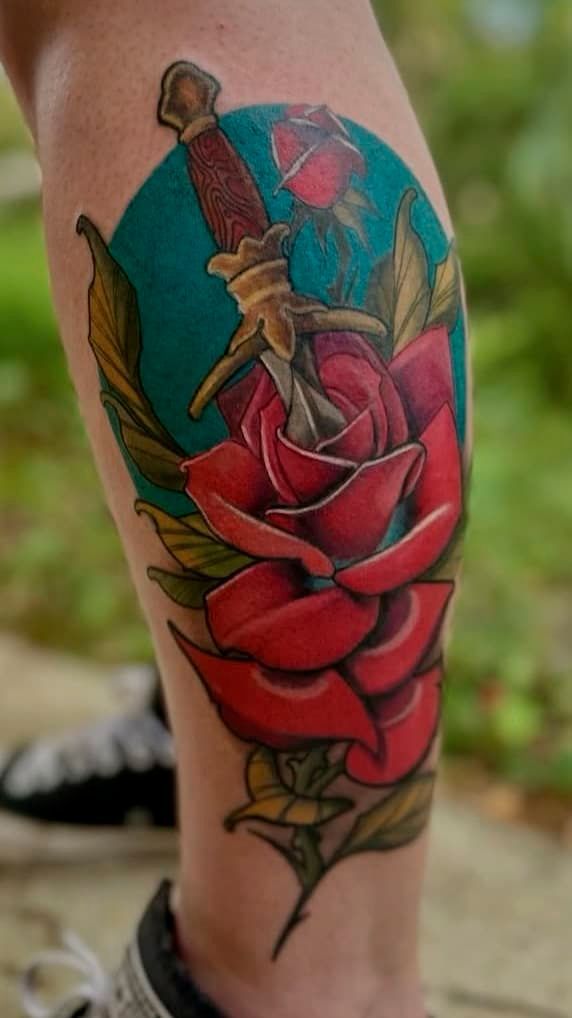 Colorful rose and butterfly tattoo on a person's calf