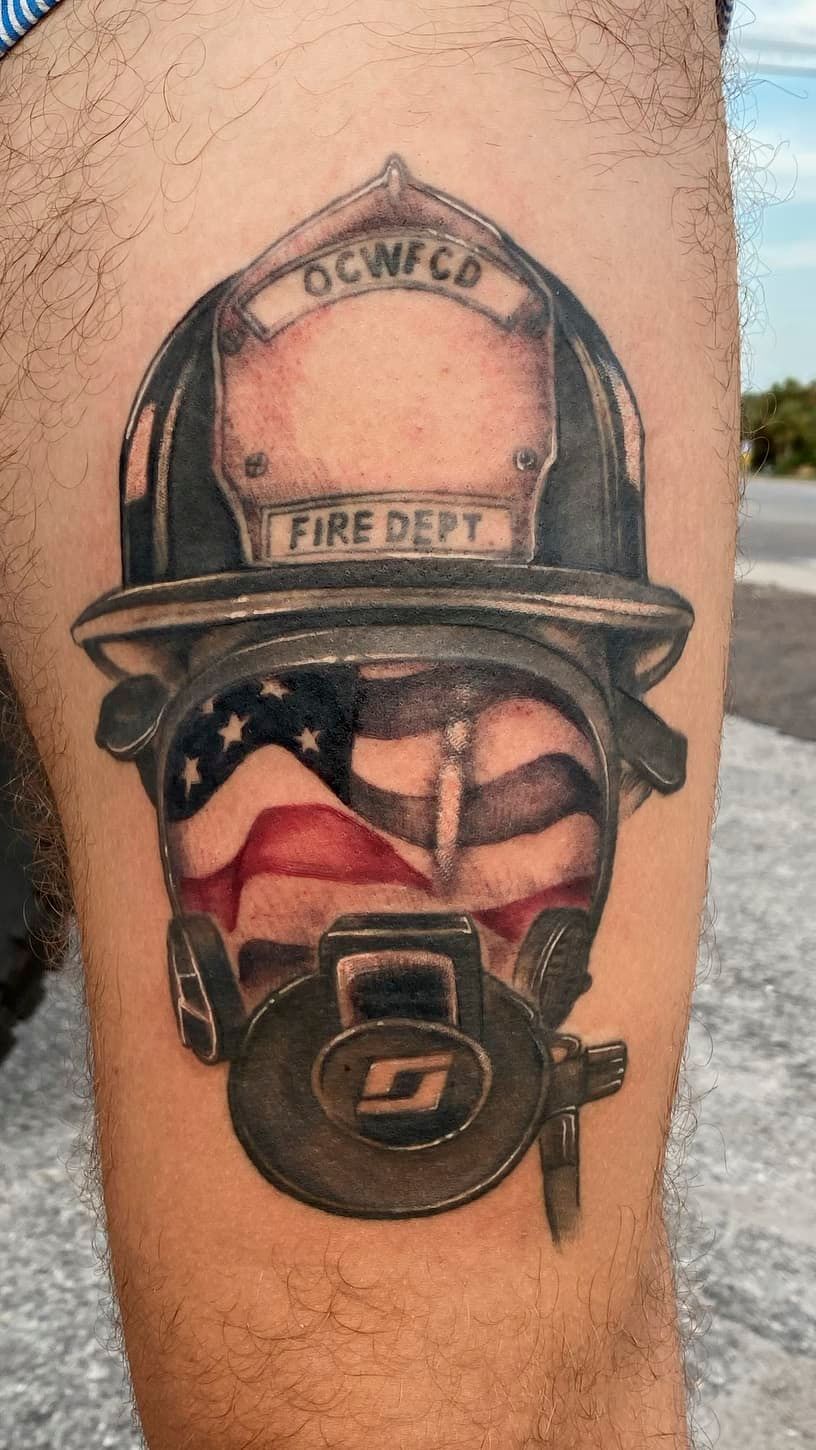 Tattoo of a firefighter helmet and face mask on a person’s upper arm