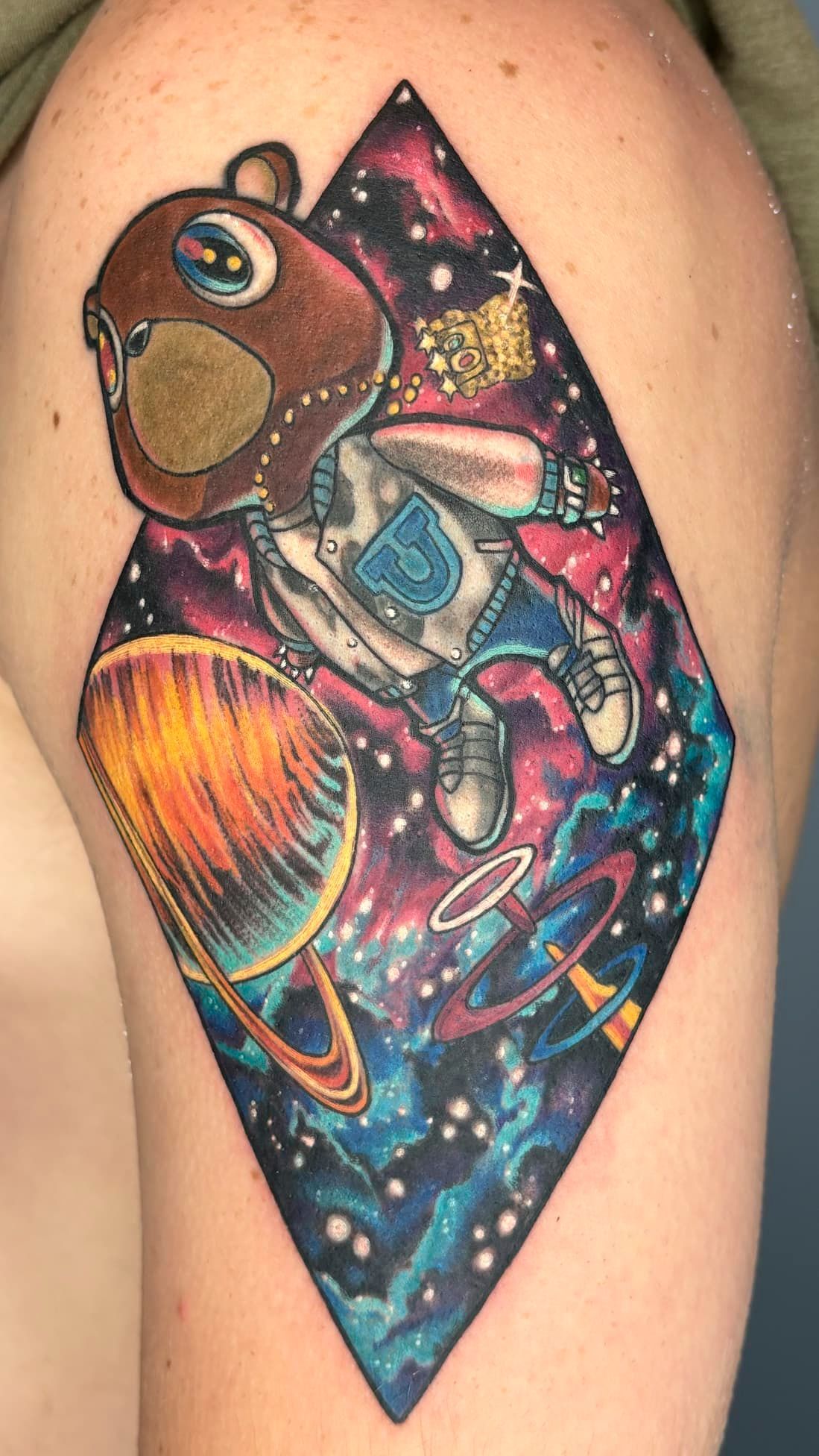 Colorful geometric tattoo of an astronaut and bird in a space-themed design on an arm