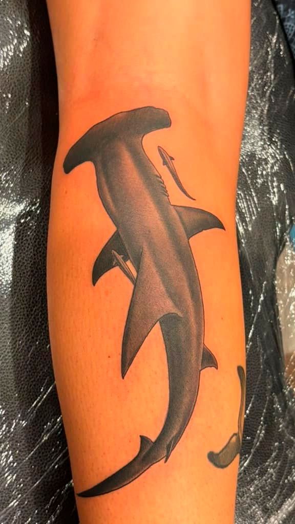 Black dolphin tattoo on an orange-painted leg.