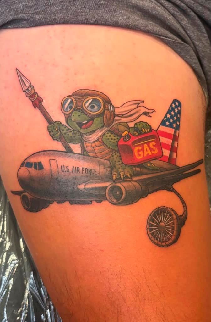 Cartoon astronaut tattoo on skin riding a rocket with a U.S. flag and “GAS” sign
