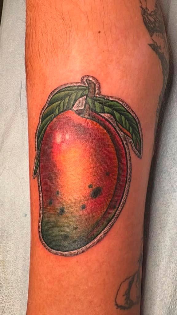 Red and green fruit tattoo on a person’s arm