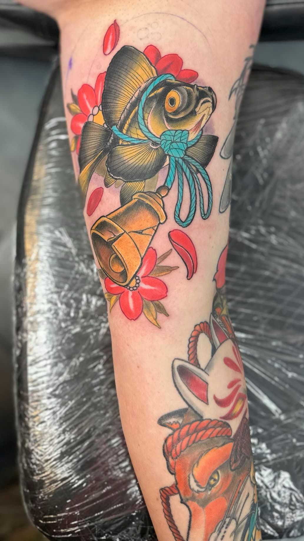 Colorful koi fish and flowers tattoo on a tattooed lower leg