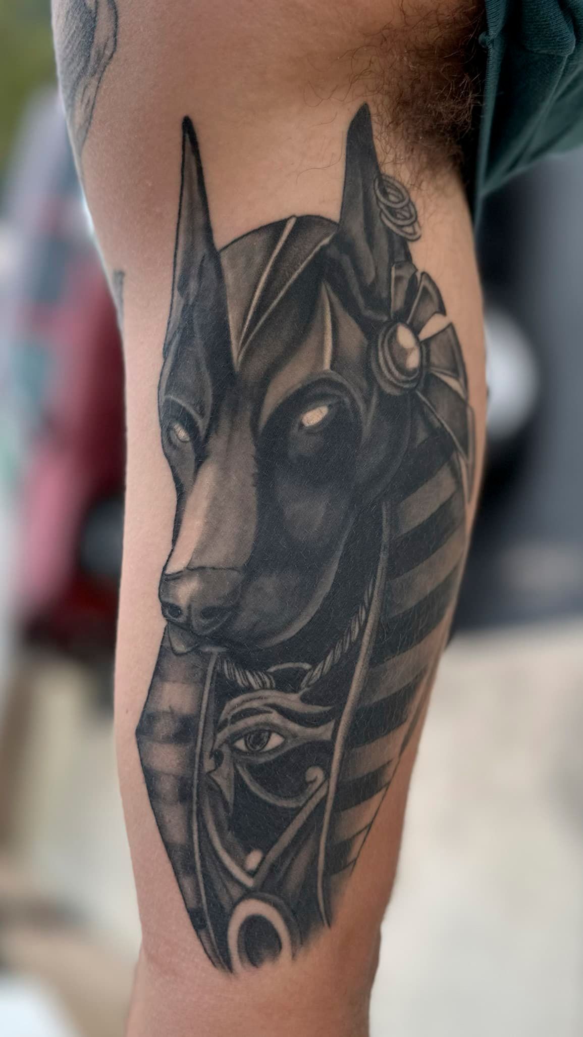 Black-and-gray tattoo of a dog’s face on a person’s calf, with pointed ears and dark shading