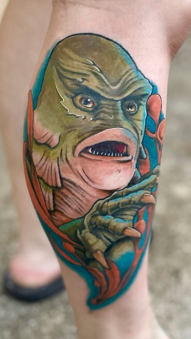 Colorful tattoo of a green-faced monster with red eyes on a calf