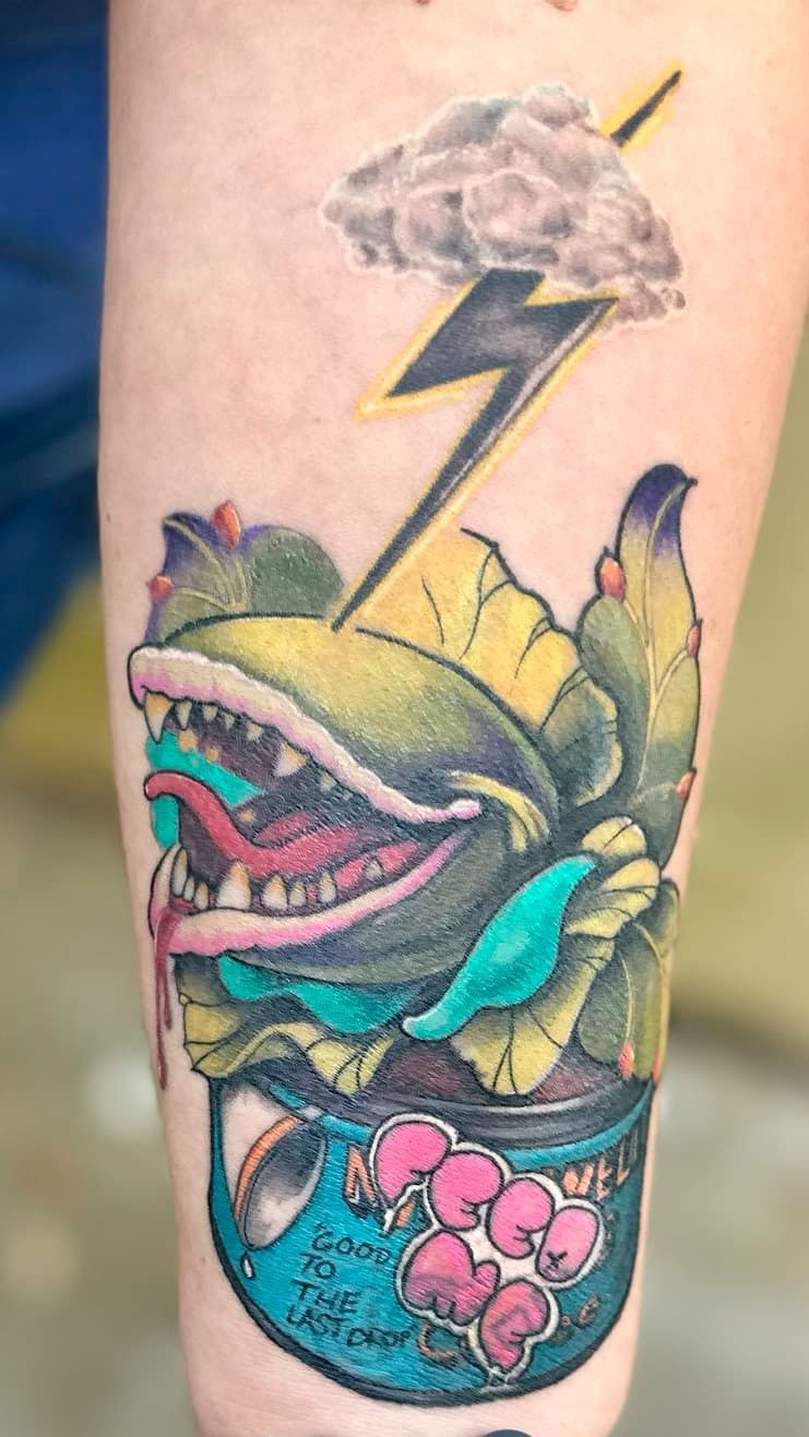 Tattoo of a colorful Venus flytrap in a can with a lightning bolt and storm cloud above