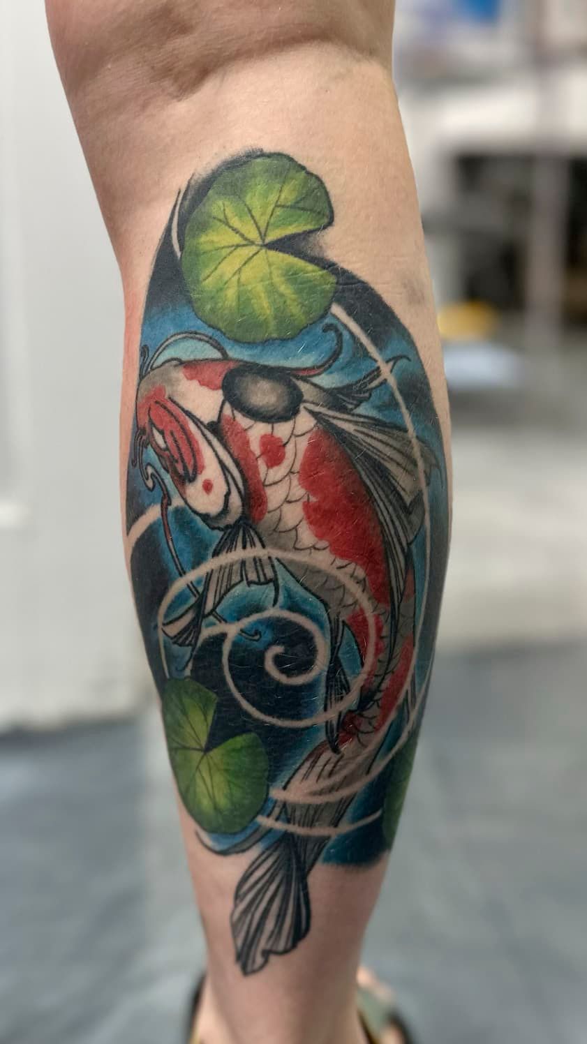 Colorful koi fish tattoo on a lower leg, with blue, red, and green accents.