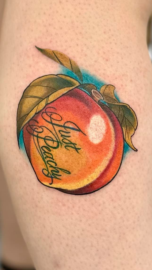 Colorful peach tattoo with “stay peachy” script on a forearm