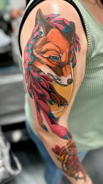 Close-up of a colorful fox tattoo on an upper arm with pink, orange, teal, and black accents