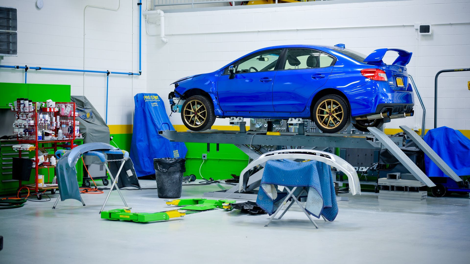Blue Car Lifted On Hydraulic Platform For Service | D&V Autobody